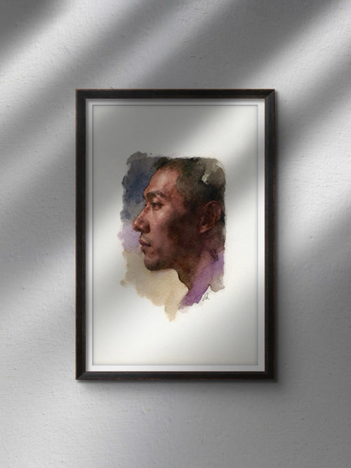 Black-framed watercolor painting of a seated male figure with detailed facial features, set against a neutral wall.
